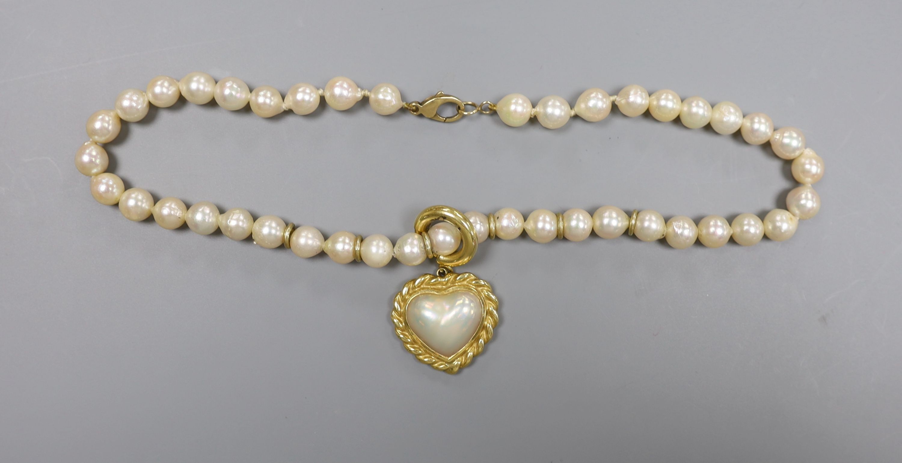 A 1960's single strand cultured pearl necklace, with an 18ct gold and mother of pearl set heart shaped pendant, necklace 39cm, pendant 25mm, gross weight 62.1 grams.